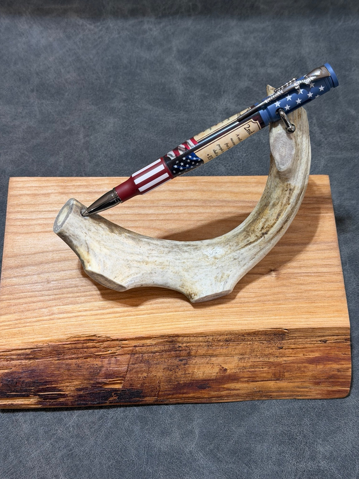 Handcrafted .30 caliber bolt action pen with red, white, and blue 2nd Amendment custom blank and chrome accents displayed on antler stand