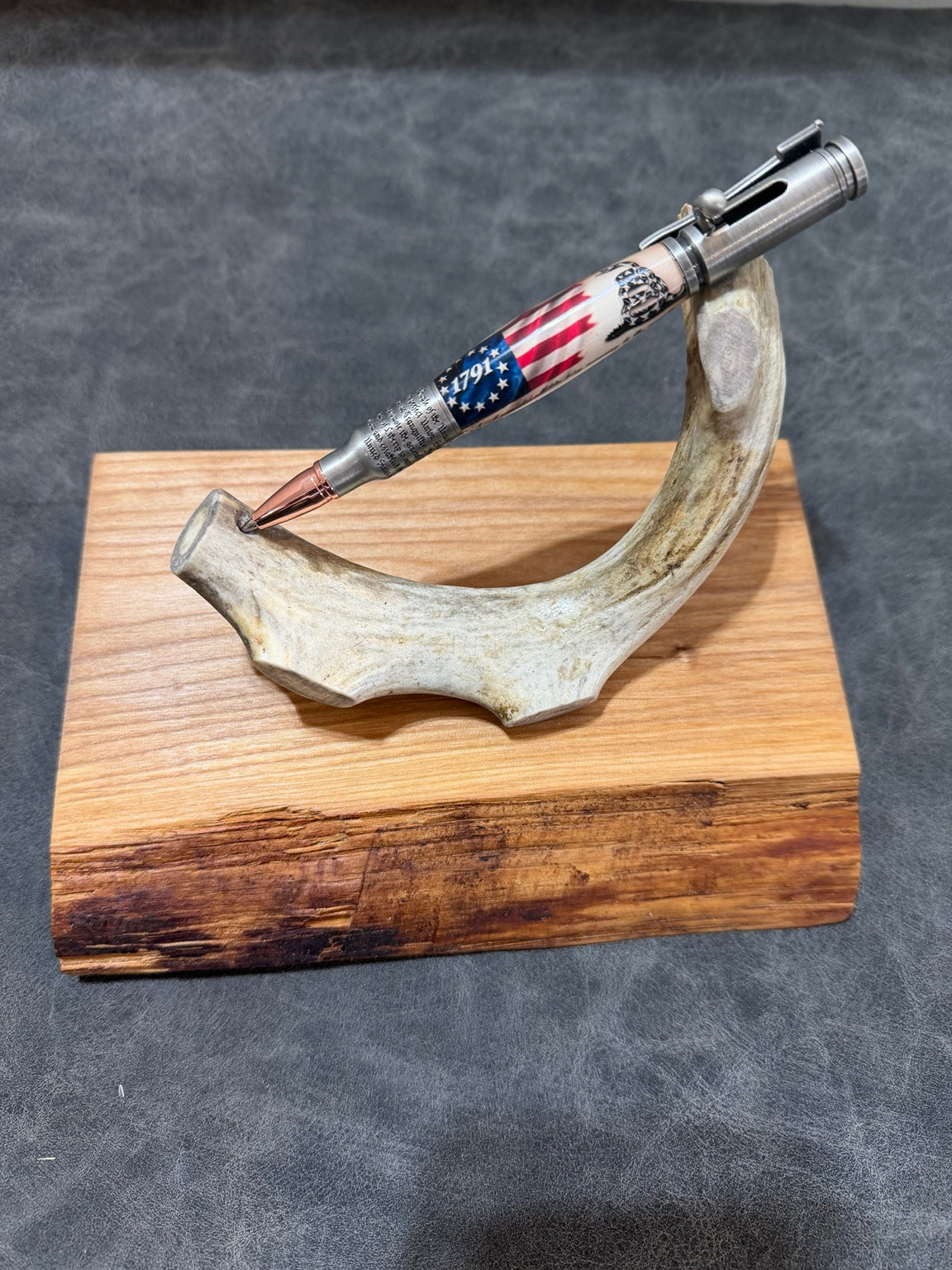 Handcrafted 1791 Don't Tread on Me bolt-action pen with antique pewter hardware and copper accents displayed on an antler stand