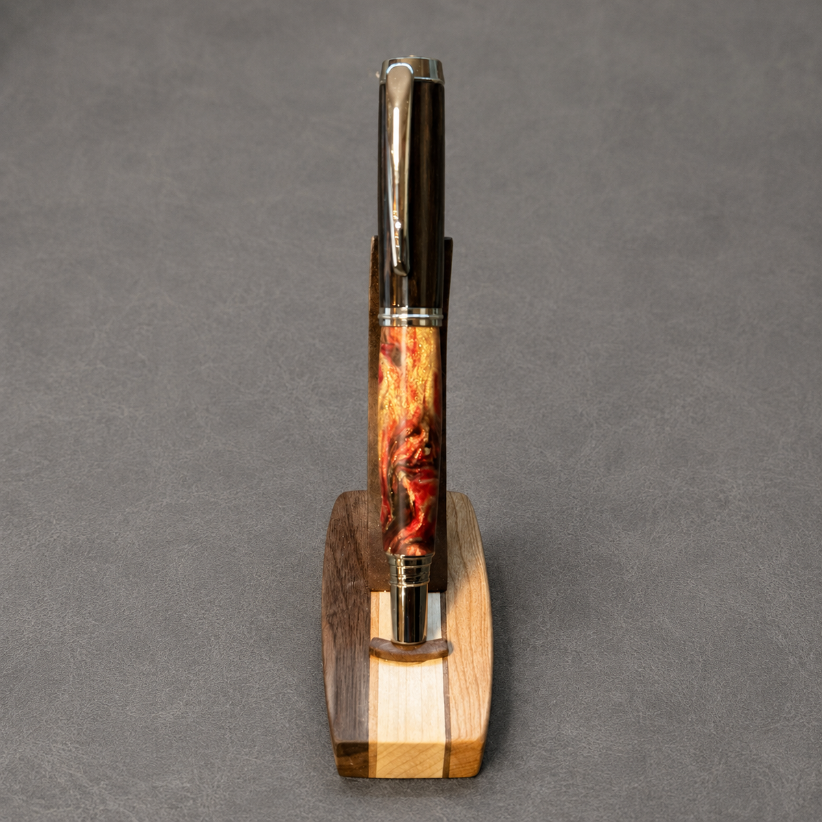 Premium rollerball pen with an African Blackwood cap, molten red and gold acrylic lower barrel, and black titanium with chrome hardware
